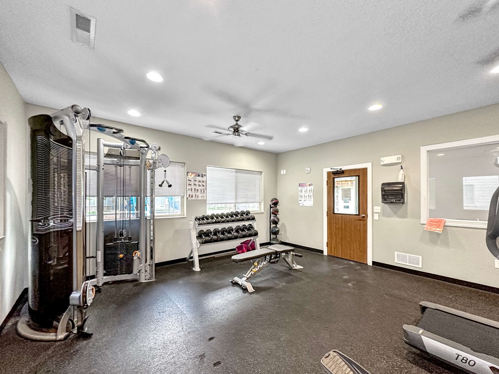 A gym with a row of treadmills and a bench.