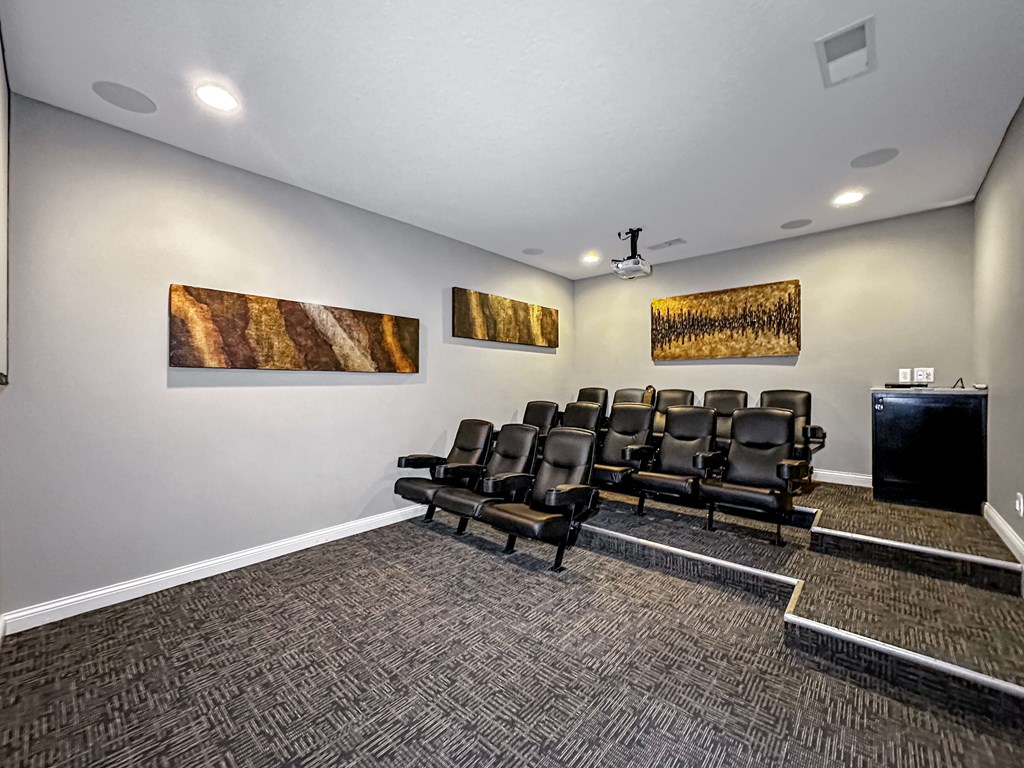 A room with a row of black chairs and a television.