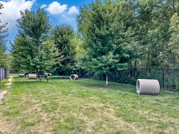 A park with grass, trees, and hay bales.