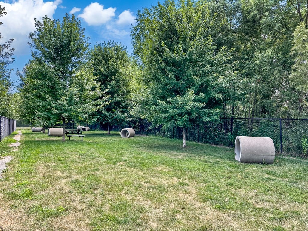 A park with grass, trees, and hay bales.