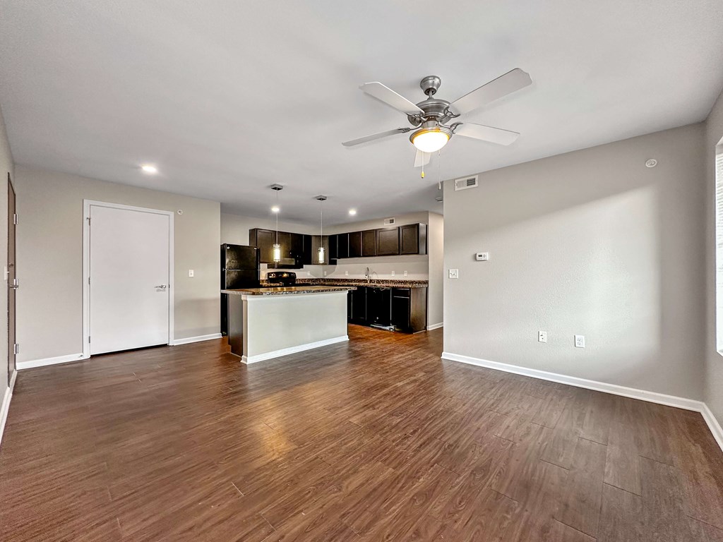 A spacious room with a ceiling fan and wooden flooring.