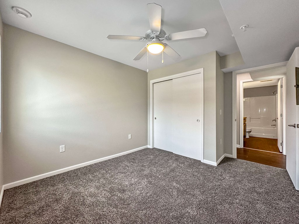 A room with a ceiling fan and carpeted floor.