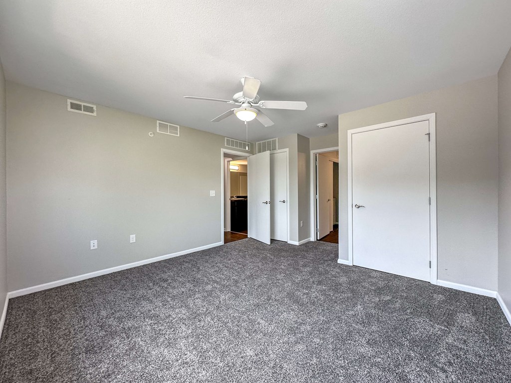A room with a ceiling fan and carpeted floor.