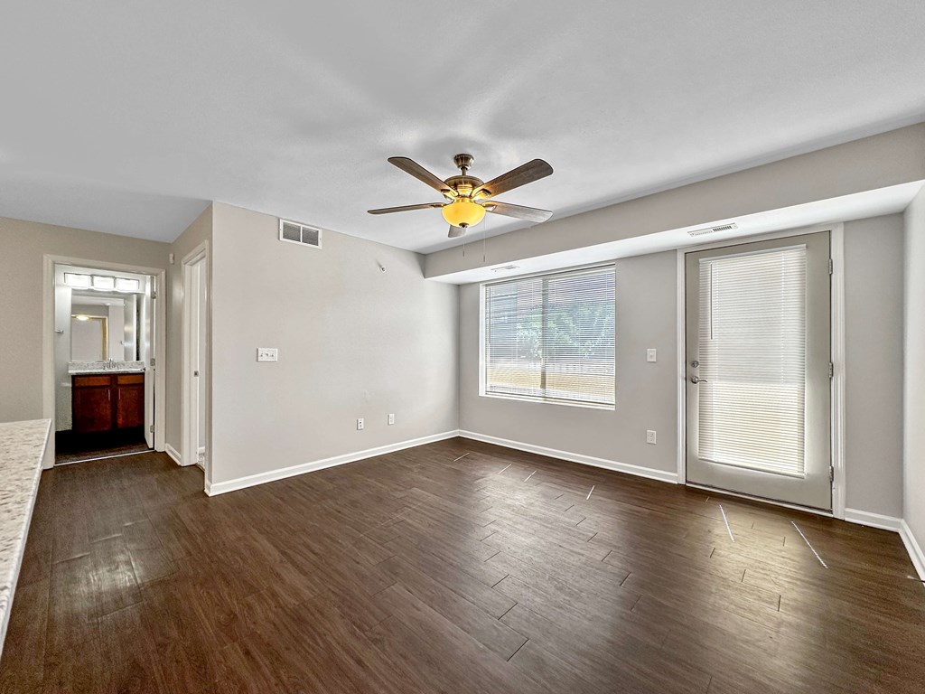 A room with a ceiling fan and sliding glass doors.