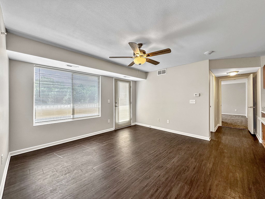 A room with a ceiling fan and wooden flooring.