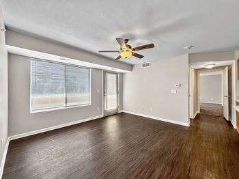 A room with a ceiling fan and wooden flooring.