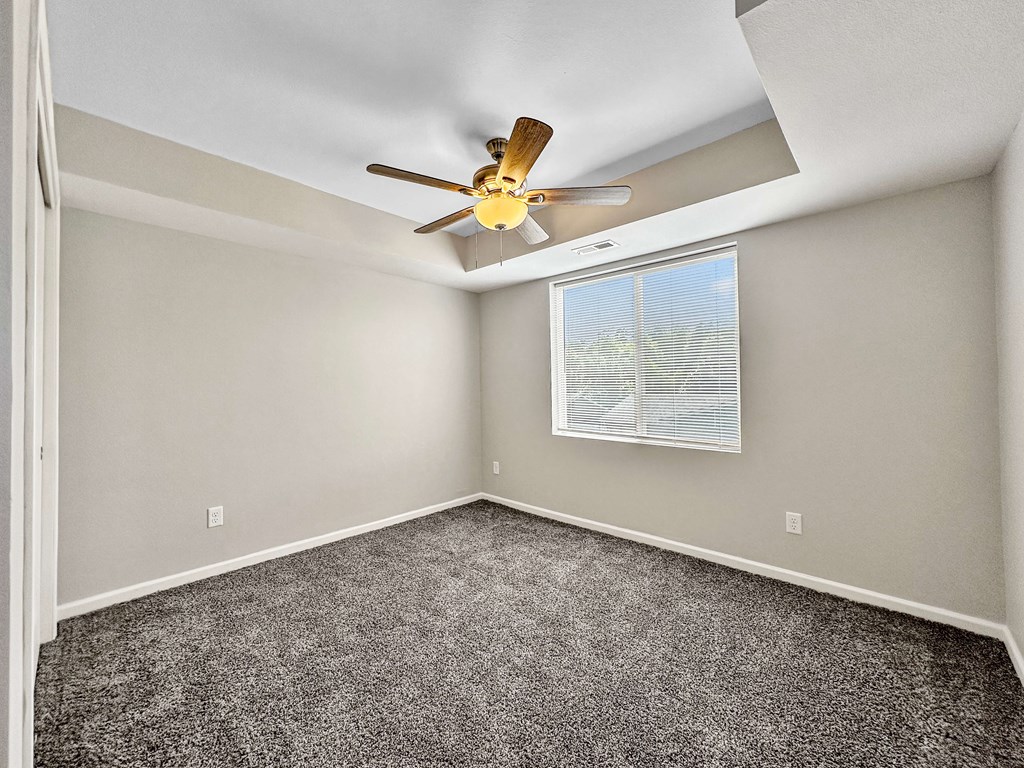 A room with a ceiling fan and a window with blinds.
