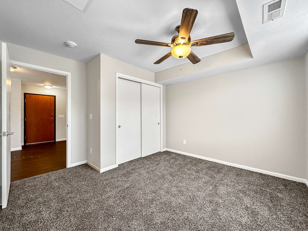 A room with a ceiling fan and carpeted floor.
