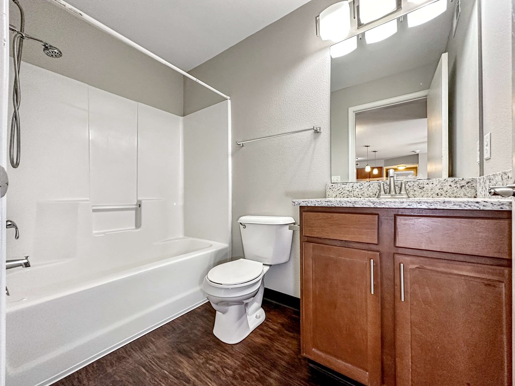 A white toilet sits in a bathroom with wooden cabinets.