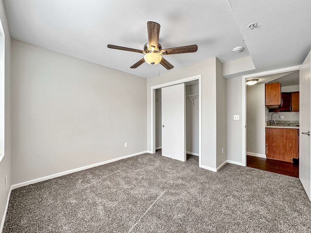 A room with a ceiling fan and carpeted floor.