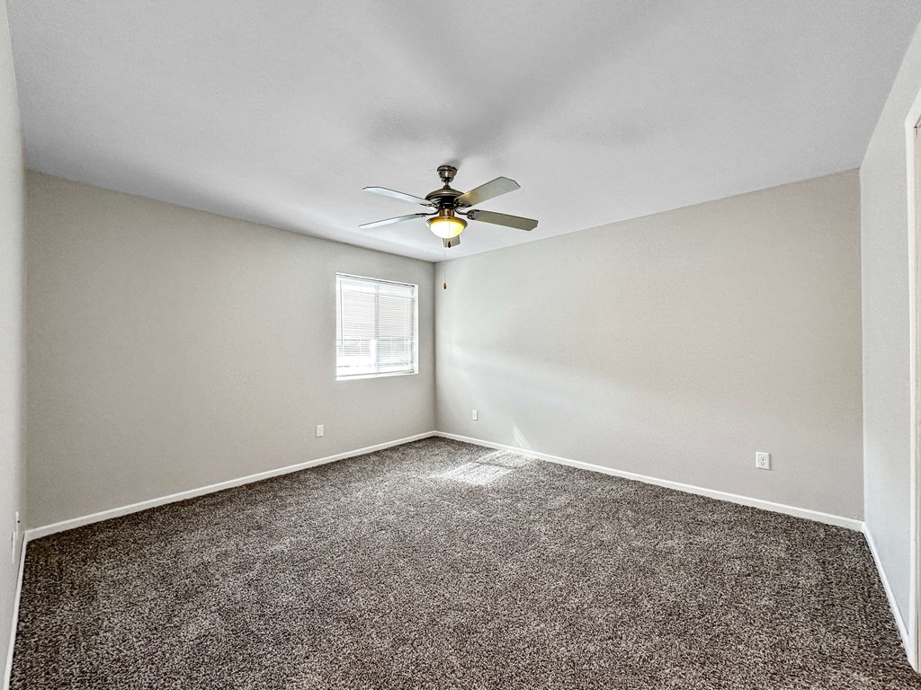 A room with a ceiling fan and carpeted floor.