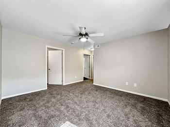 A room with a ceiling fan and carpeted floor.