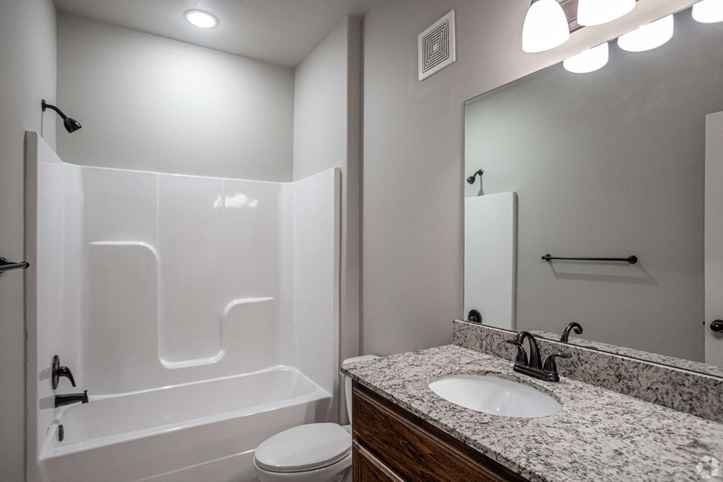 the retreat guest bathroom with granite counter top and white shower and tub