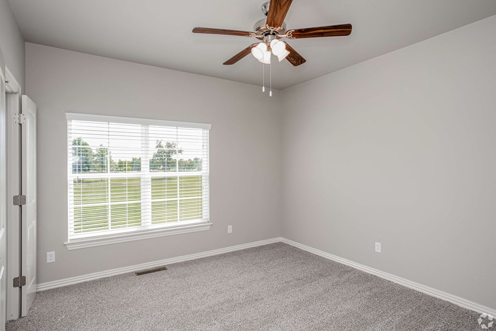 an empty bedroom with a ceiling fan and a window