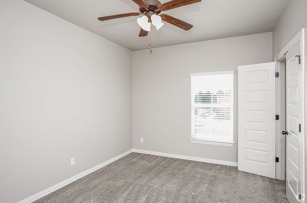 an empty bedroom with a ceiling fan and a closet