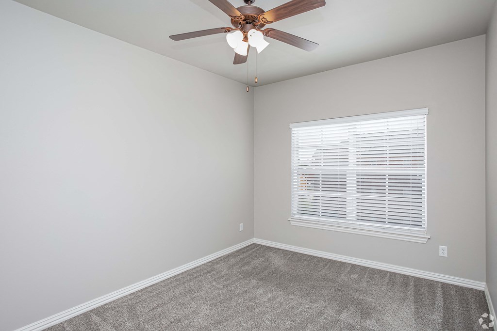 an empty room with a ceiling fan and a window