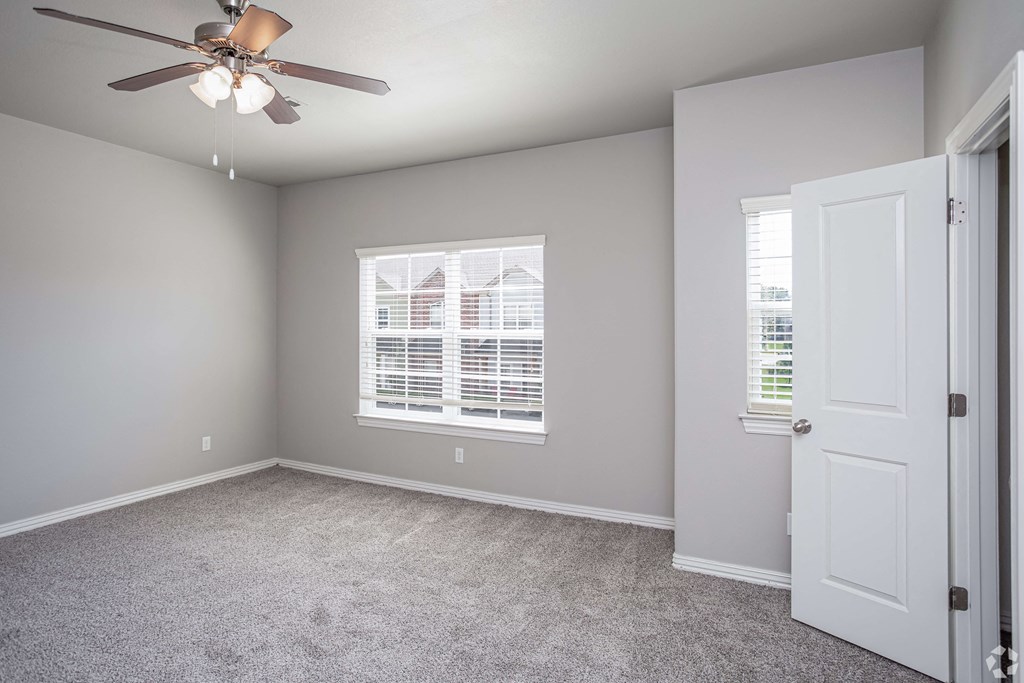 an empty bedroom with a ceiling fan and a door