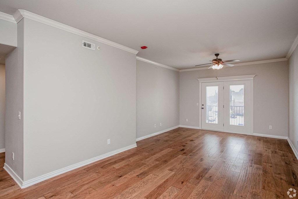 an empty living room with wood floors and a ceiling fan