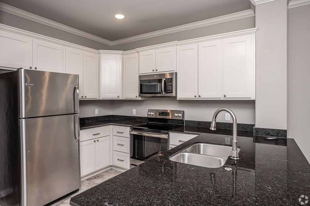 a kitchen with granite counter tops and white cabinets