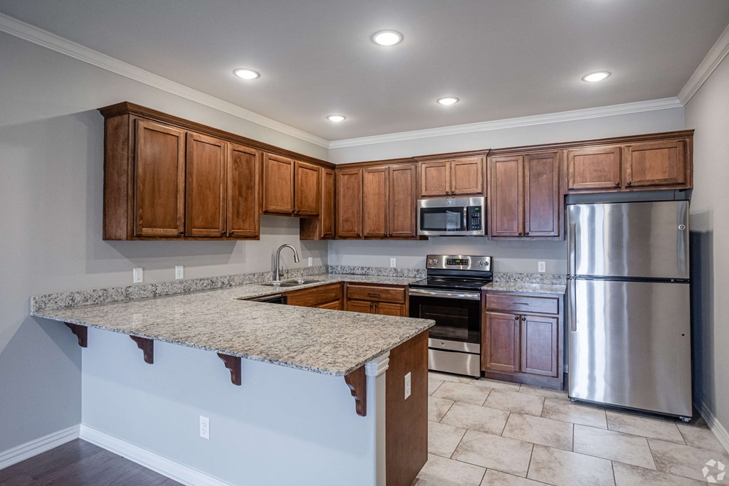 an empty kitchen with granite counter top and stainless steel appliances