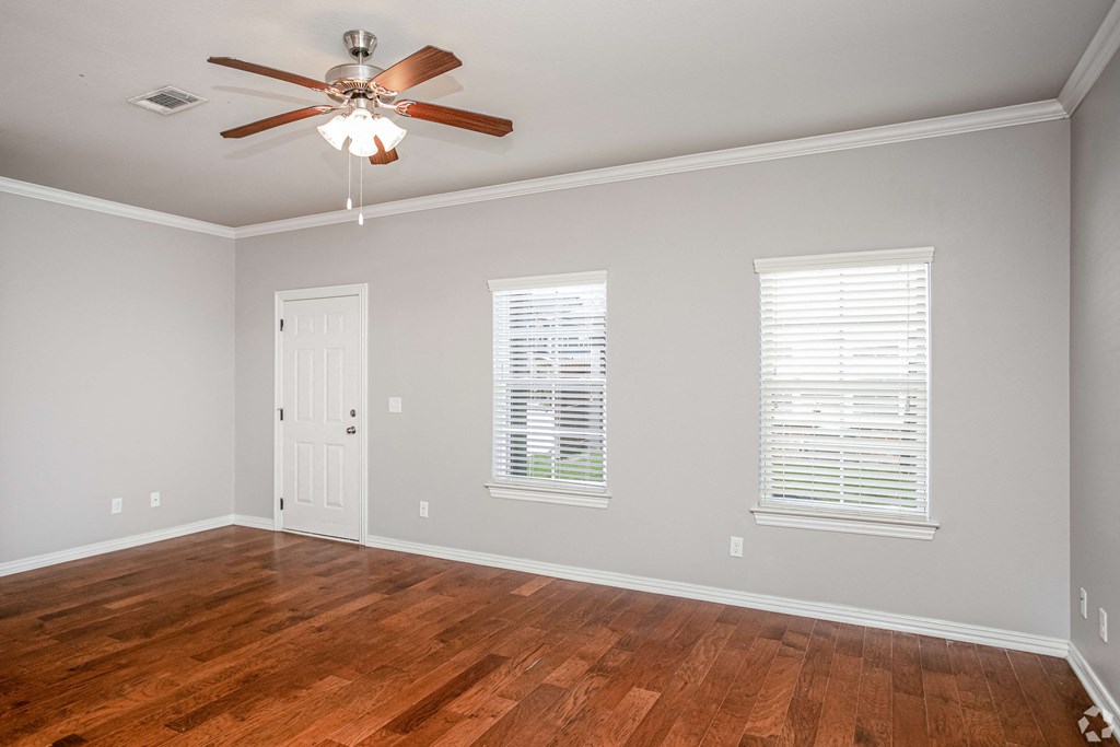 an empty living room with wood floors and a ceiling fan
