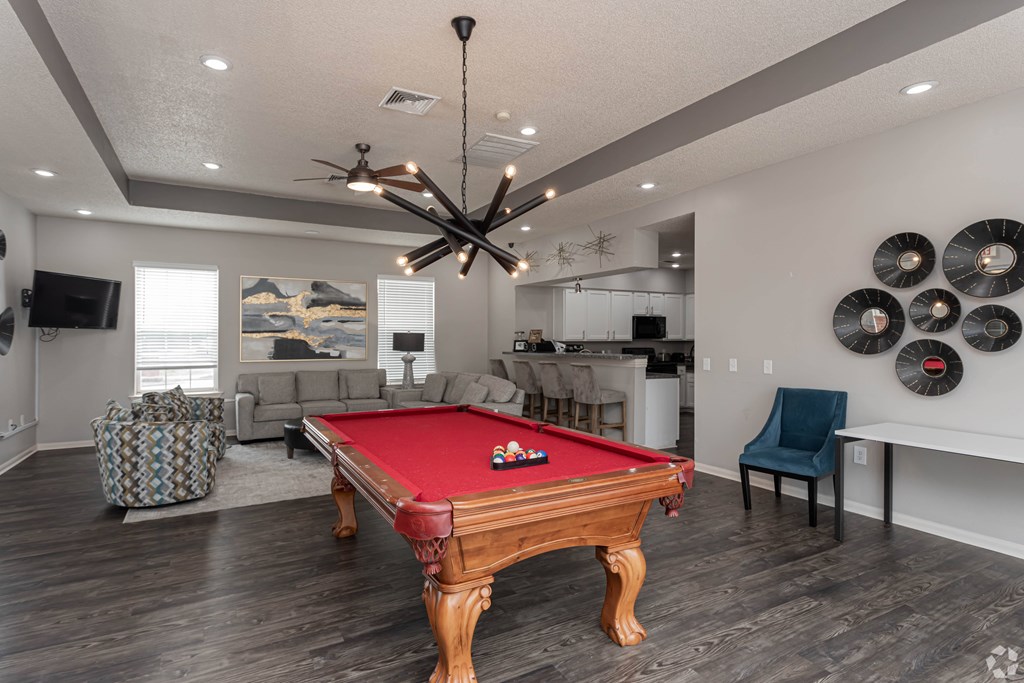 A pool table is in the middle of a room with a ceiling fan and a chair.