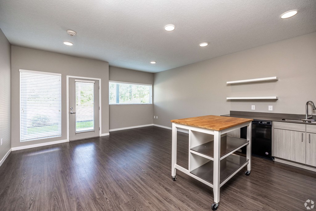 an empty living room with a table and a kitchen