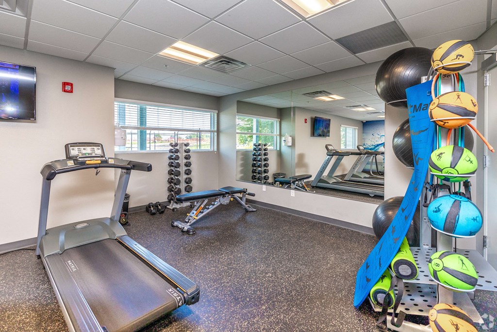 a gym with exercise equipment and weights in the corner of a room