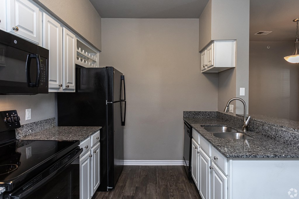 a kitchen with black appliances and granite counter tops and white cabinets