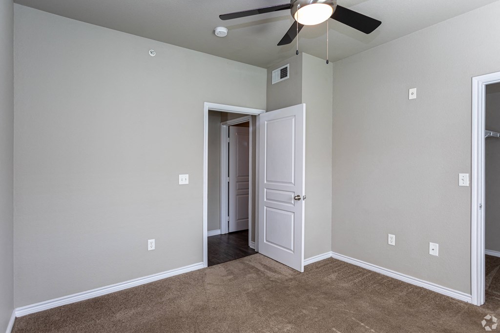 an empty room with a ceiling fan and a door to a closet