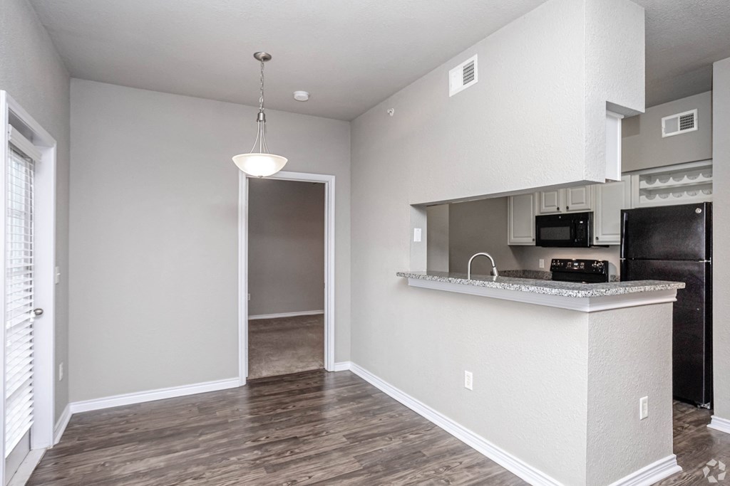 an empty apartment with a kitchen and a door to the living room