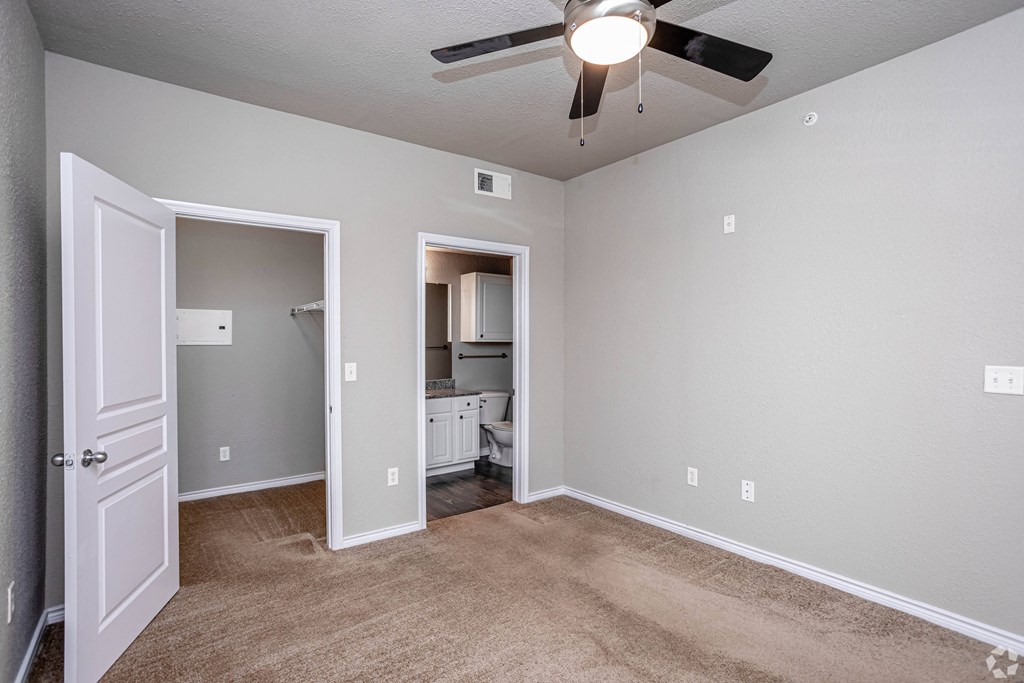 an empty room with a ceiling fan and a door to a bathroom
