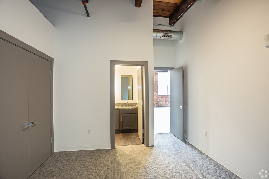 an empty hallway with a door to a bathroom and a doorway to a bedroom