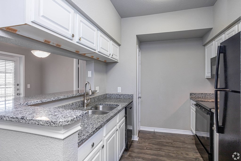 an empty kitchen with white cabinets and granite counter tops