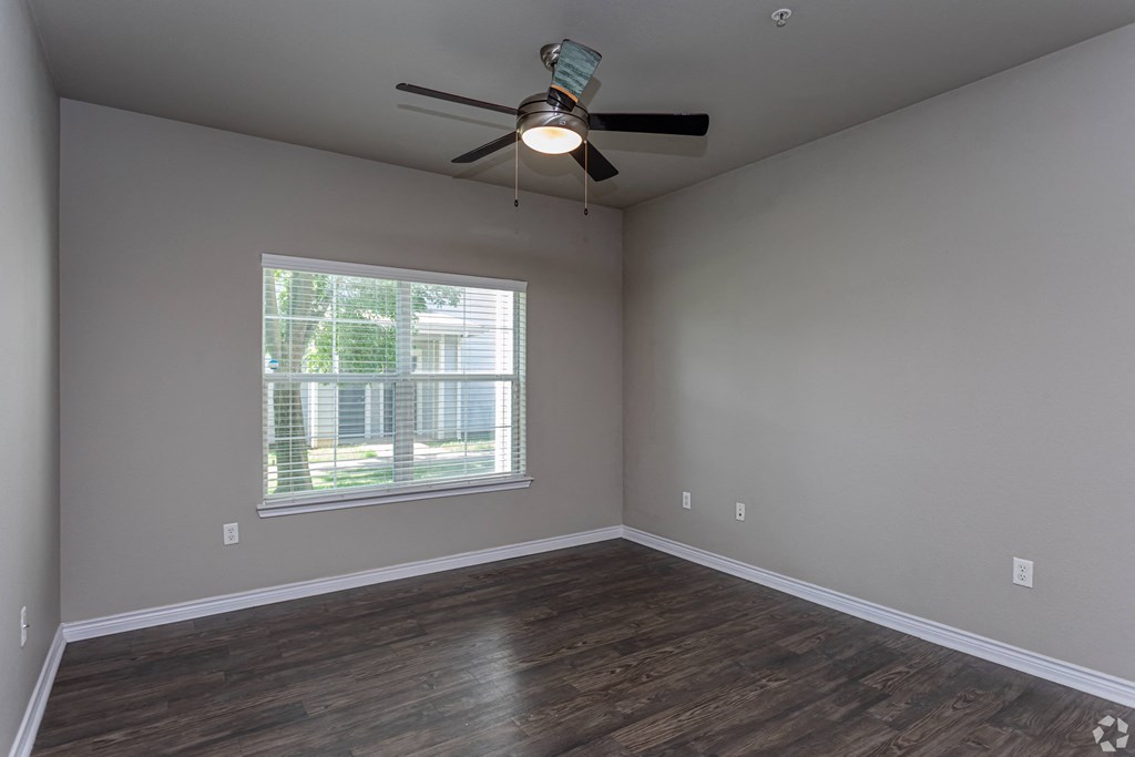 an empty living room with a ceiling fan and a window