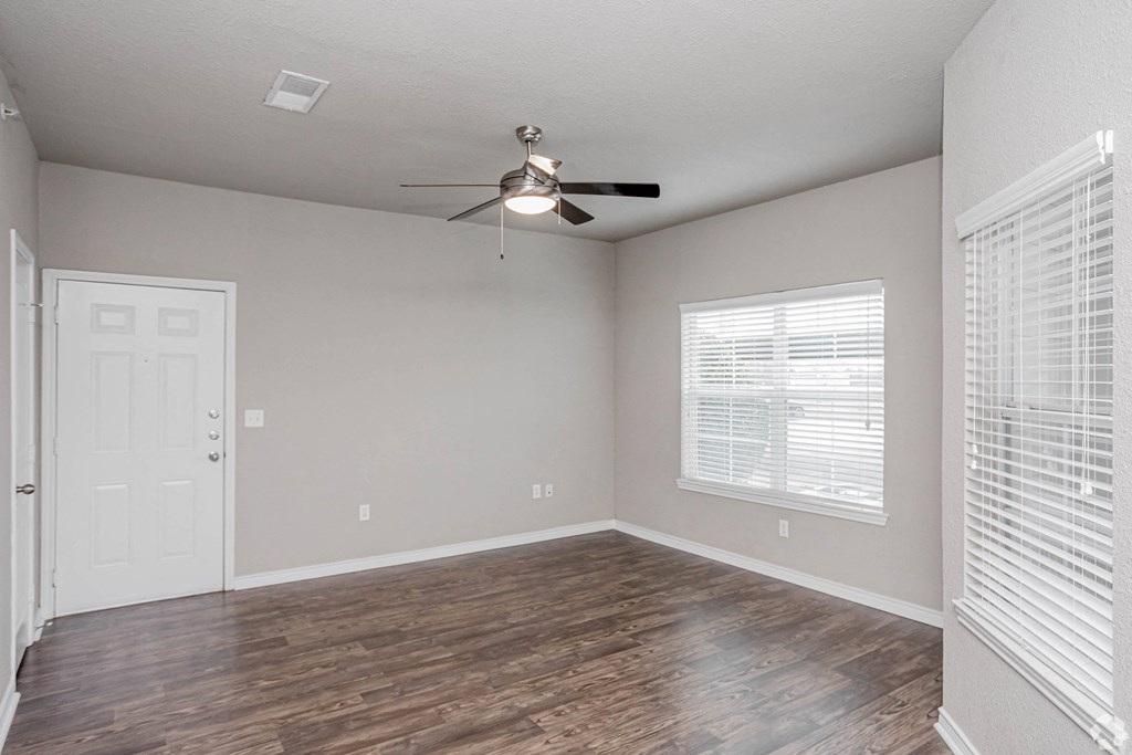 an empty living room with a ceiling fan and a window