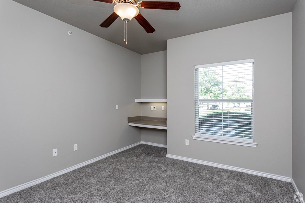 an empty room with a ceiling fan and a window