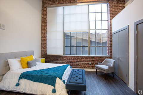 a bedroom with a large bed and a brick wall