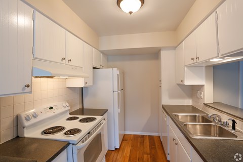 A kitchen with white cabinets and a stove top oven.