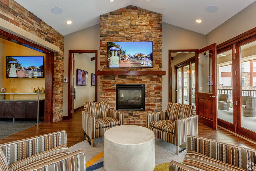 A living room with a stone fireplace and striped couches.