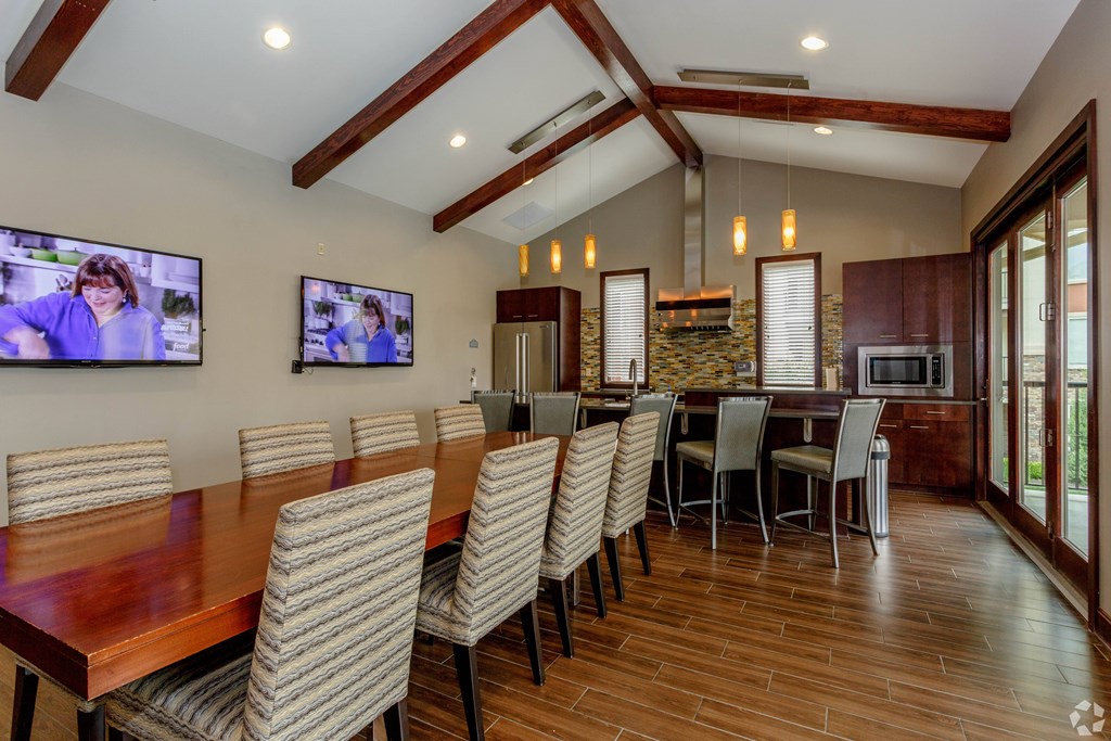 A modern dining room with a long wooden table and chairs.