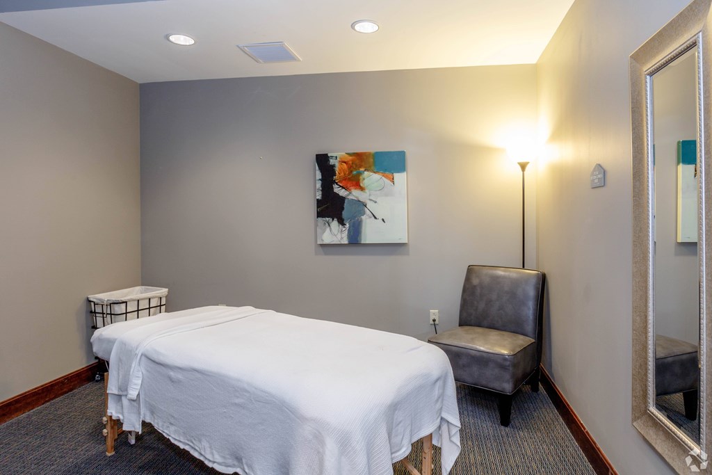 A bedroom with a bed, chair, and painting on the wall.