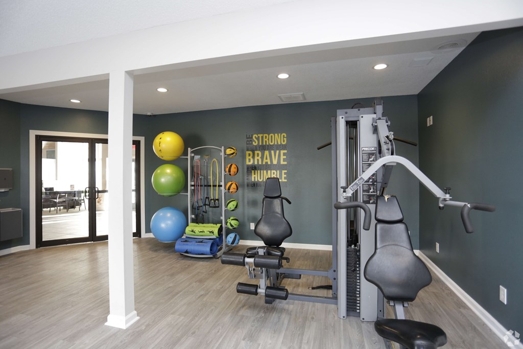 A gym with a wall that says "Strong Brave Honest" and a variety of equipment.