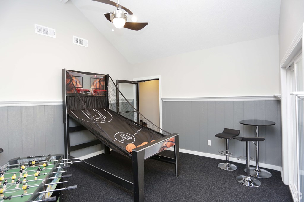 A room with a foosball table and air hockey table.