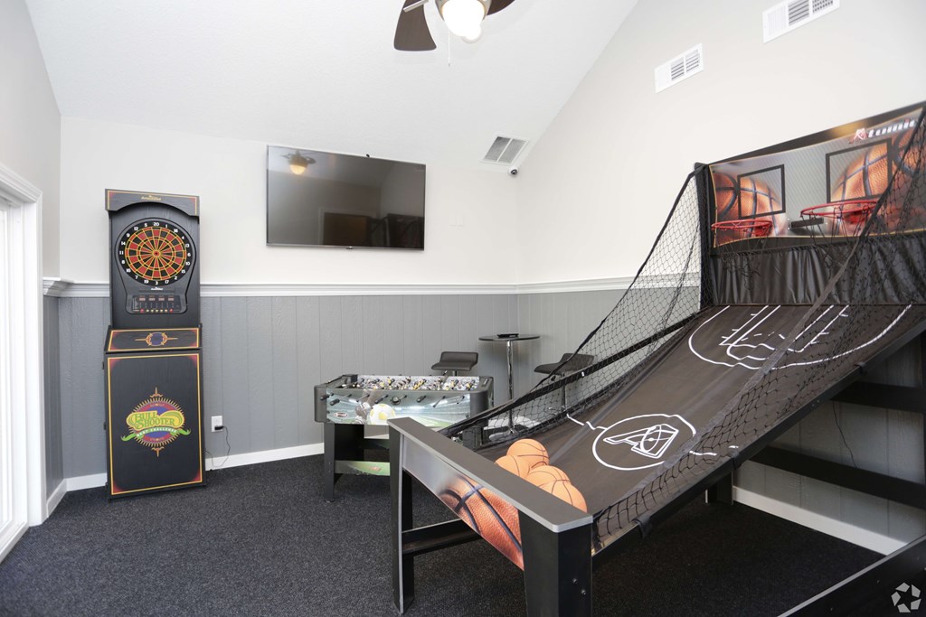 A bowling alley is set up in a room with a TV and a refrigerator.