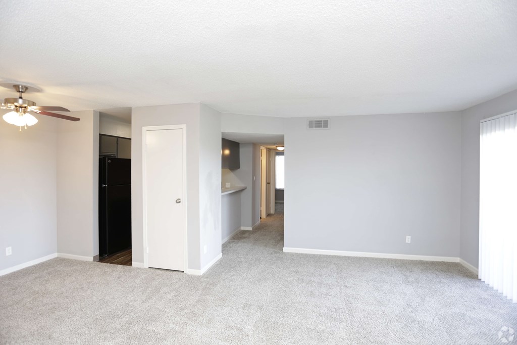 A spacious room with a ceiling fan and carpeted floor.