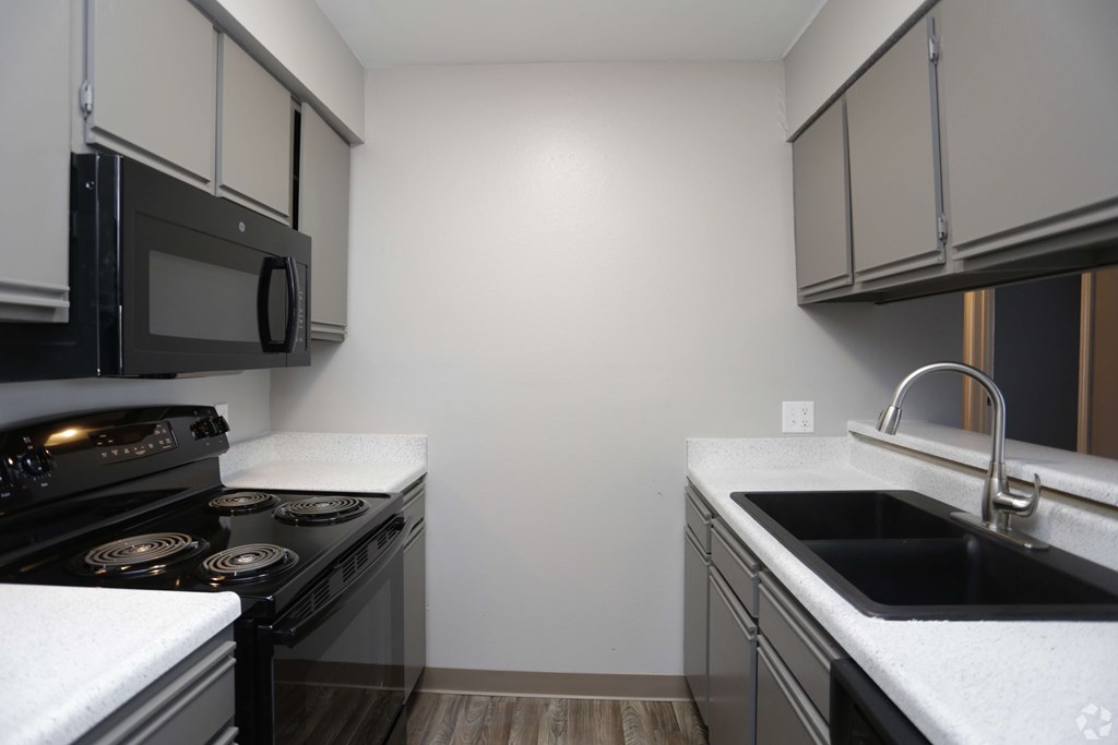 A kitchen with a black stove and a black microwave.