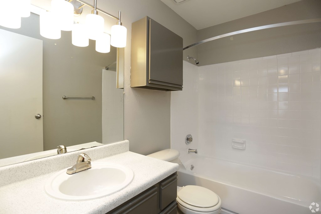 A white sink with a gold faucet is on a countertop in a bathroom.