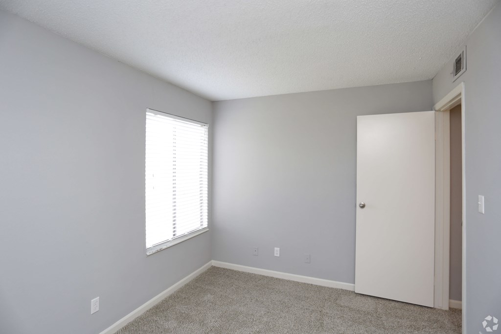 A room with a white door and a window with blinds.