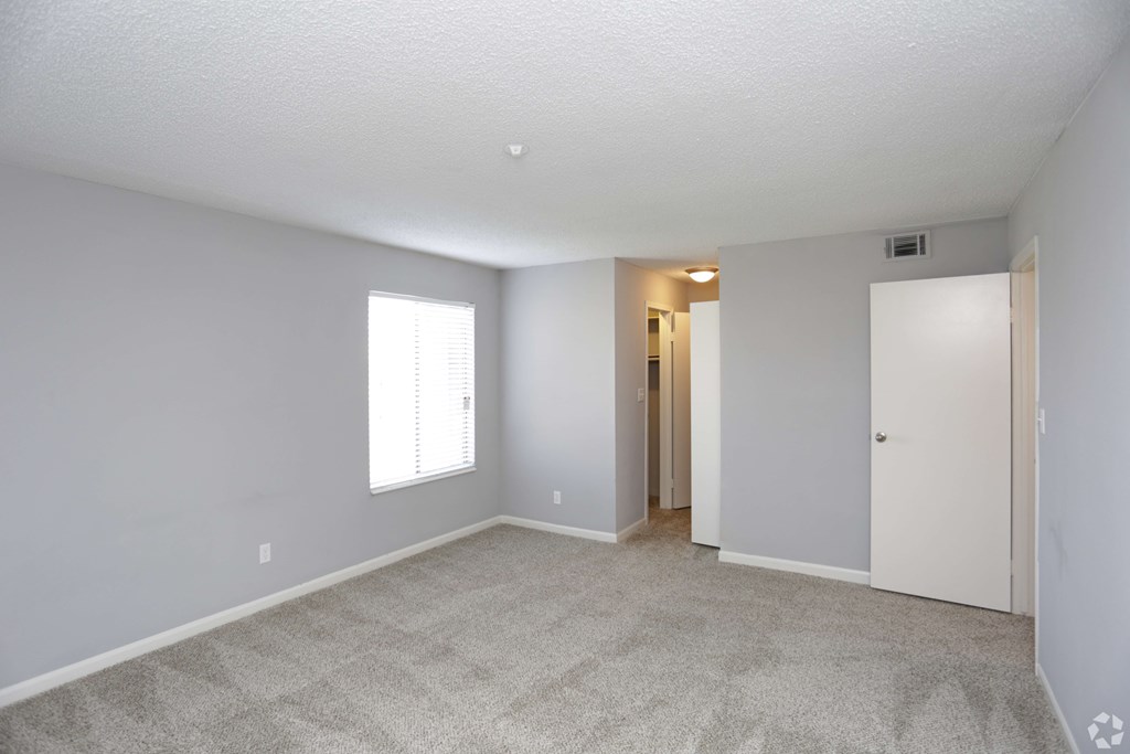 A room with a carpeted floor and a window.